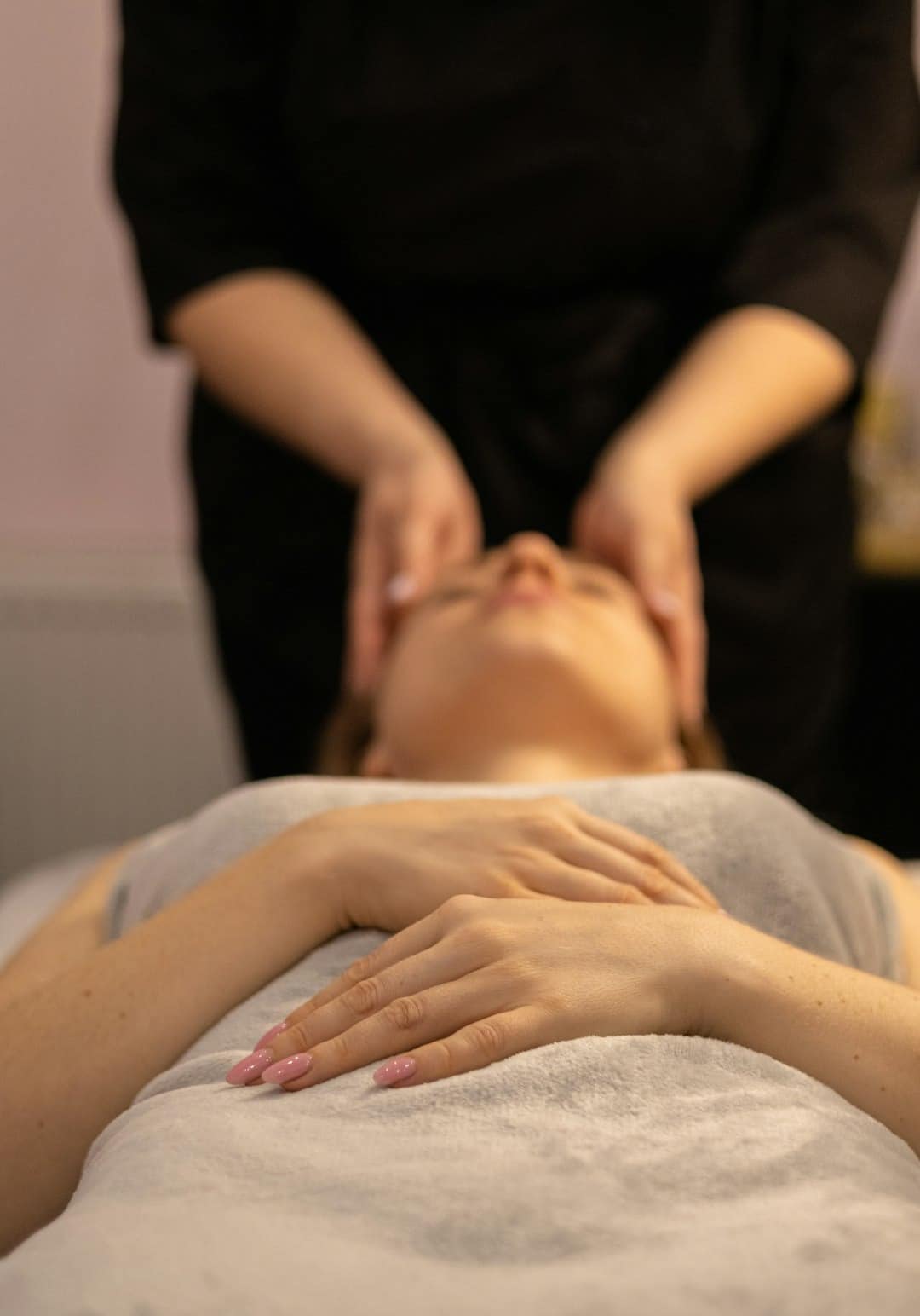 A spa professional gives a facial massage to a relaxed woman.